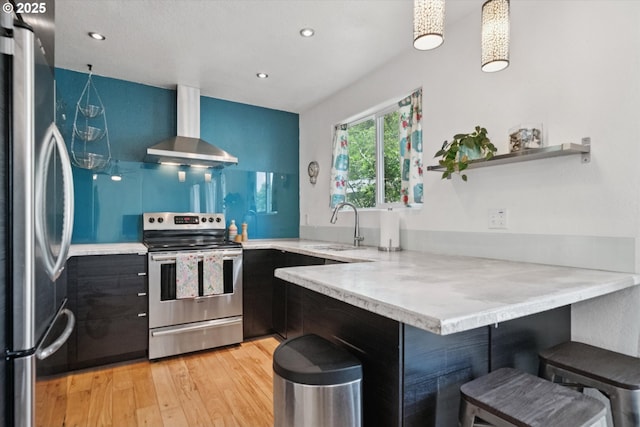 6035 NE 9th Ave, Portland, OR 97211 - kitchen featuring appliances with stainless steel finishes, wall chimney exhaust hood, a peninsula, light wood finished floors, and a breakfast bar