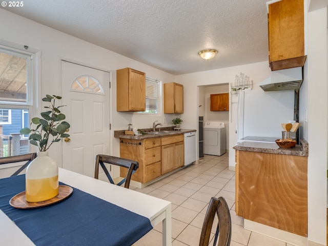 kitchen featuring washer / dryer, plenty of natural light, dark countertops, a sink, and a textured ceiling