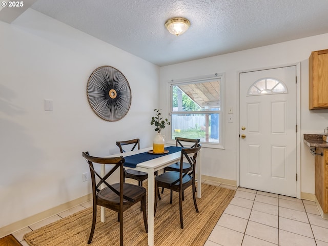 dining area featuring light tile patterned floors, a textured ceiling, and baseboards
