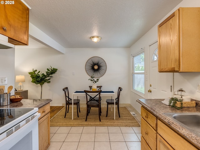 kitchen featuring light tile patterned floors, white electric stove, a textured ceiling, a sink, and dark countertops