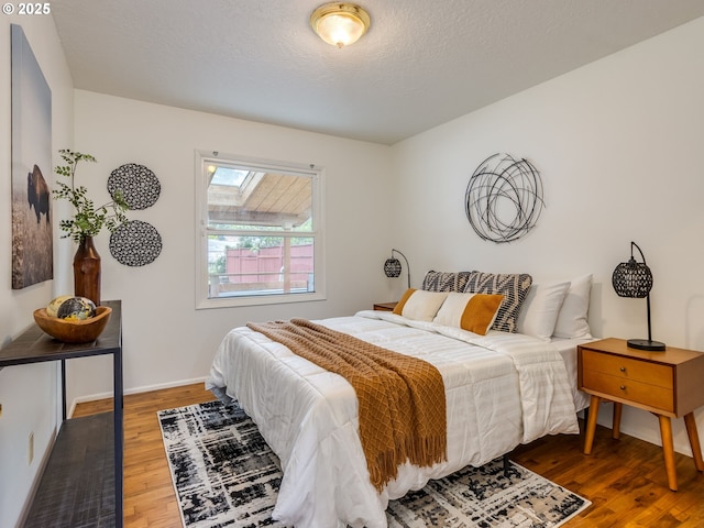 bedroom featuring wood finished floors, a skylight, and baseboards