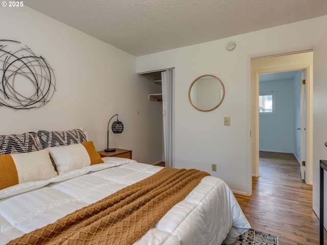 bedroom featuring wood finished floors, baseboards, and a closet