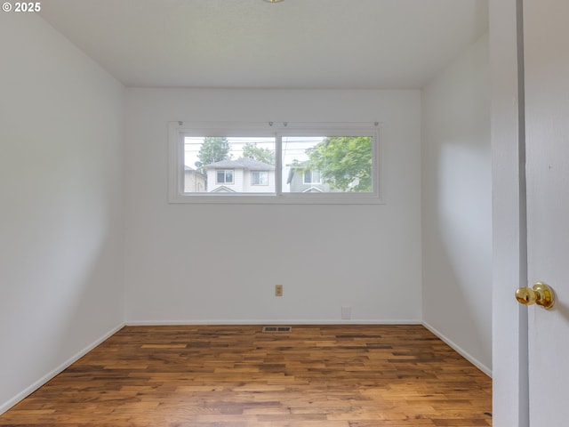 spare room featuring plenty of natural light, wood finished floors, and baseboards