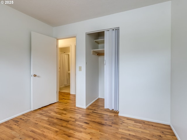 unfurnished bedroom featuring light wood finished floors, a closet, and baseboards