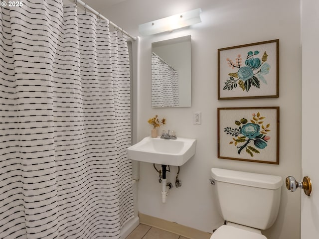 bathroom featuring toilet, tile patterned floors, a sink, and a shower with curtain