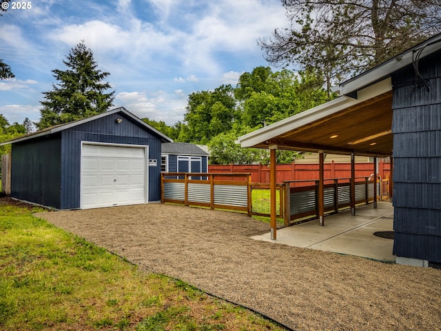 view of yard featuring an outdoor structure, a detached garage, and driveway