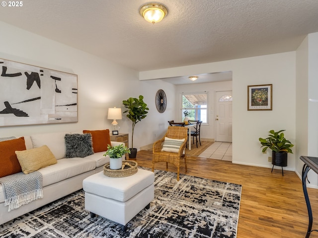 living area featuring wood finished floors, baseboards, and a textured ceiling