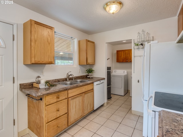 kitchen featuring washer / dryer, a sink, white appliances, light tile patterned flooring, and dark countertops