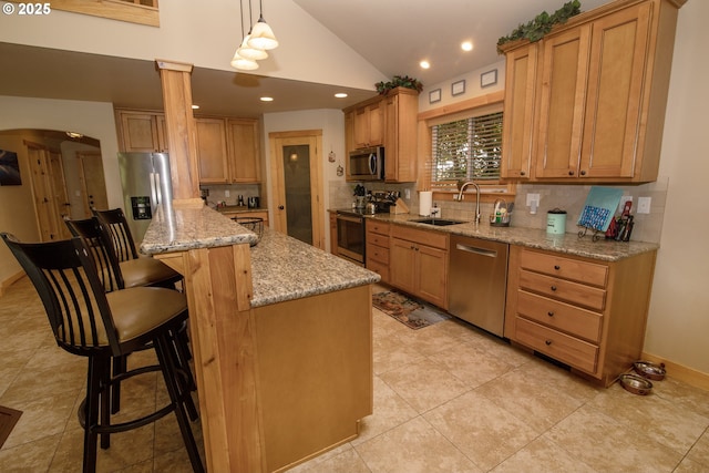kitchen with a sink, decorative backsplash, stainless steel appliances, and a kitchen breakfast bar