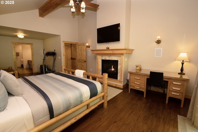 bedroom with baseboards, beam ceiling, a lit fireplace, and wood finished floors
