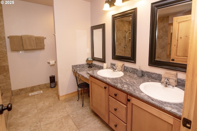 bathroom featuring a sink, baseboards, tile patterned floors, and double vanity
