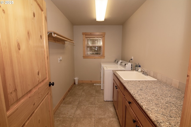 washroom featuring light tile patterned flooring, baseboards, a sink, cabinet space, and independent washer and dryer