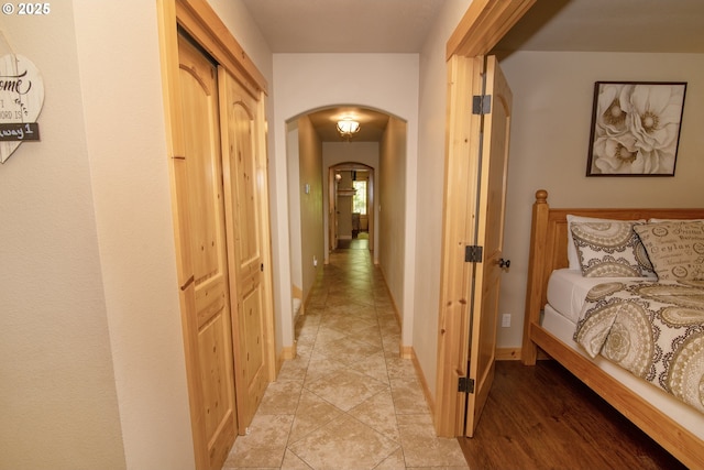 corridor featuring arched walkways and baseboards