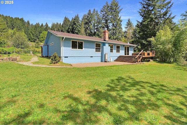 back of property with a lawn, a deck, crawl space, and a chimney