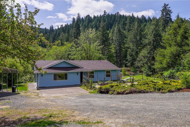 view of front of house featuring dirt driveway and a wooded view