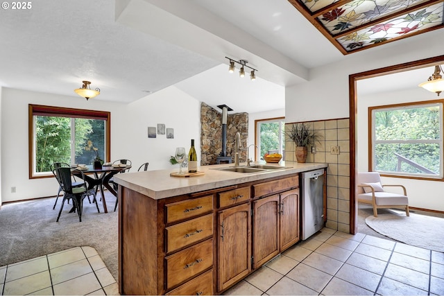 kitchen with a sink, a wood stove, dishwasher, light countertops, and a peninsula