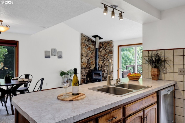 kitchen featuring light countertops, a sink, a wood stove, and dishwasher