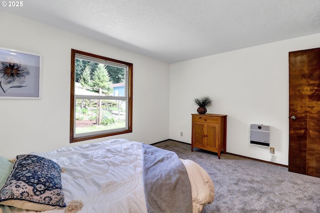 bedroom with a textured ceiling, heating unit, baseboards, and carpet