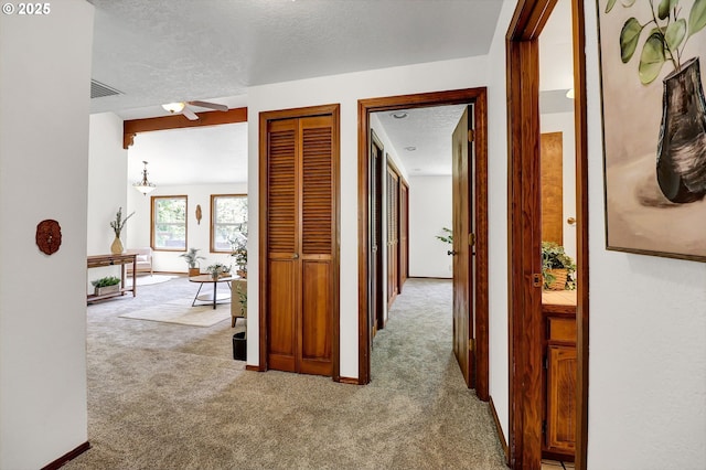 hallway featuring carpet floors, a textured ceiling, and visible vents