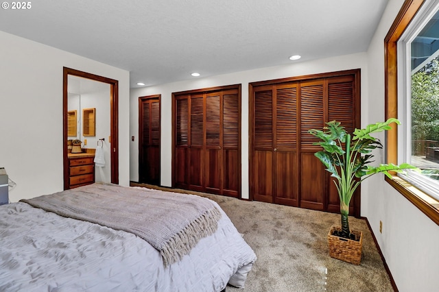 bedroom with two closets, recessed lighting, and carpet flooring