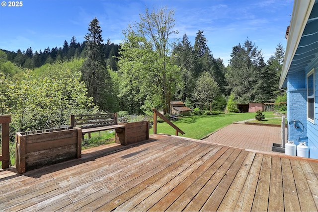 wooden deck with a lawn and a wooded view