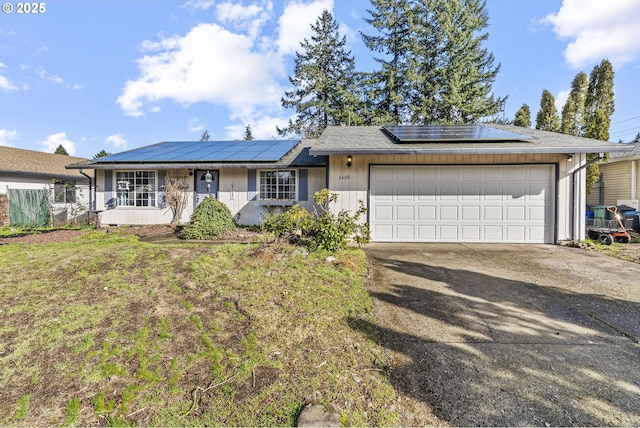 single story home featuring solar panels, concrete driveway, an attached garage, and a front yard