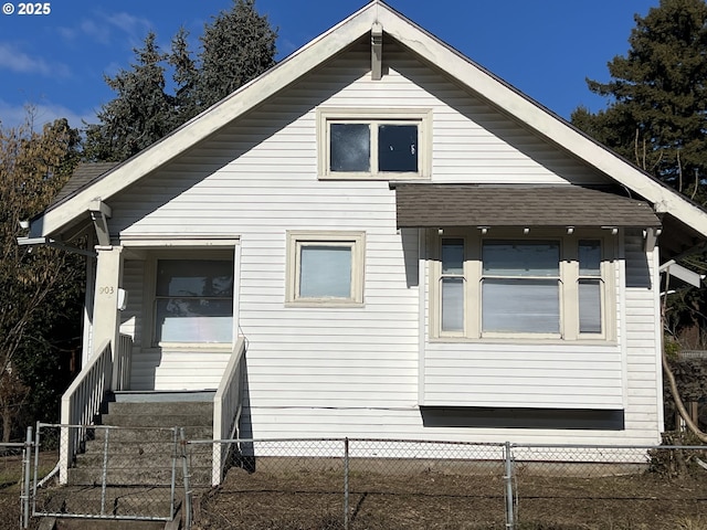 view of side of home with a shingled roof and a fenced front yard