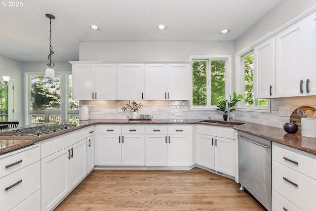 10915 SW Mourning Dove Pl, Beaverton, OR 97007 - kitchen with white cabinetry, tasteful backsplash, dark stone countertops, hanging light fixtures, and stainless steel appliances