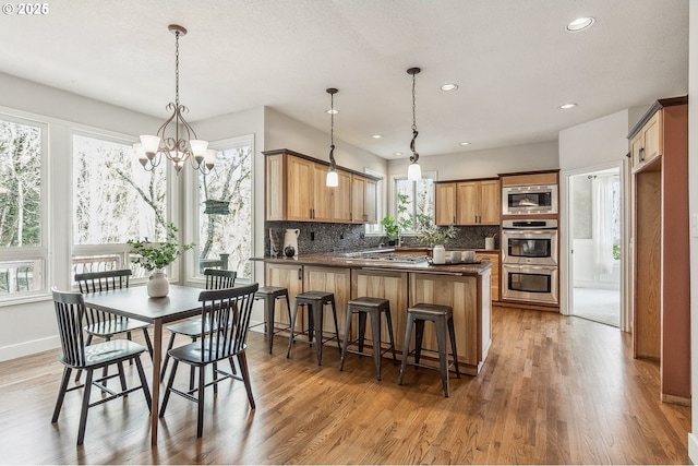 kitchen featuring stainless steel appliances, light wood finished floors, dark countertops, and decorative backsplash