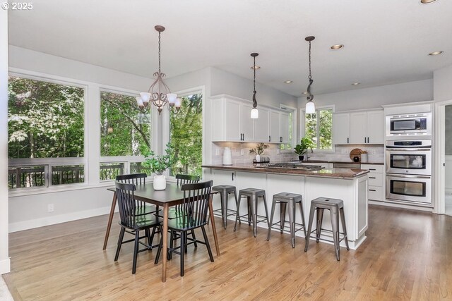 10915 SW Mourning Dove Pl, Beaverton, OR 97007 - kitchen with appliances with stainless steel finishes, backsplash, white cabinetry, and a chandelier