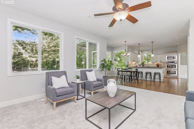 10915 SW Mourning Dove Pl, Beaverton, OR 97007 - living room with light carpet, ceiling fan with notable chandelier, recessed lighting, baseboards, and light wood-type flooring