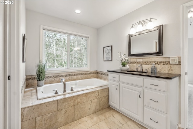 full bath featuring decorative backsplash, a bath, and vanity