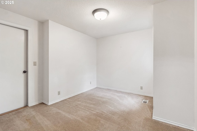 carpeted spare room with visible vents, a textured ceiling, and baseboards