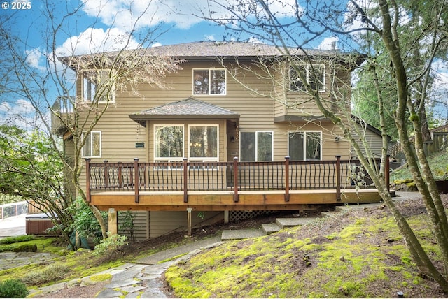 rear view of house with a deck and a hot tub