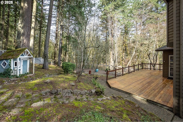 view of yard featuring a storage shed, a wooden deck, and an outdoor structure