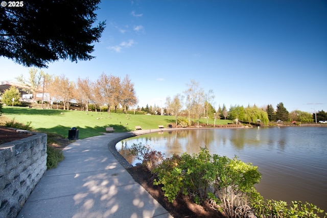 view of home's community with a water view and a lawn