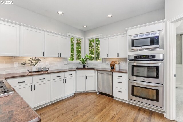 10915 SW Mourning Dove Pl, Beaverton, OR 97007 - kitchen featuring a sink, appliances with stainless steel finishes, tasteful backsplash, and light wood-type flooring