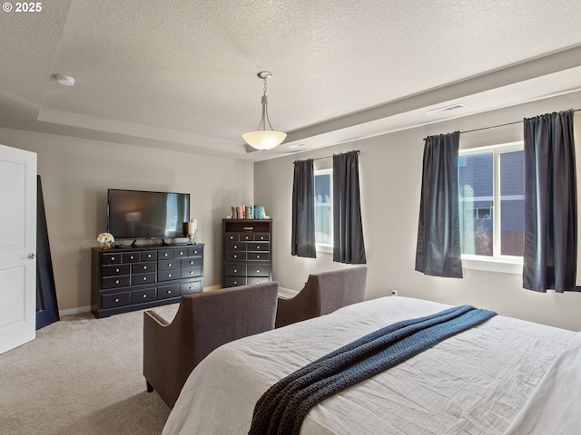 bedroom with a textured ceiling, a tray ceiling, baseboards, carpet flooring, and visible vents
