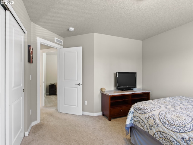 bedroom featuring a textured ceiling, a closet, light colored carpet, baseboards, and visible vents