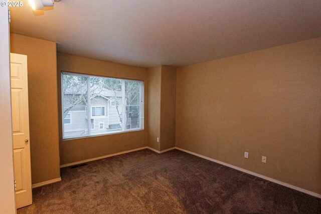 spare room with dark colored carpet