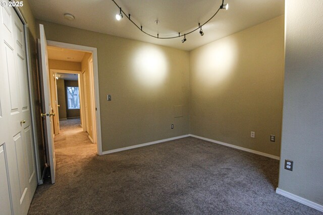 carpeted spare room with rail lighting