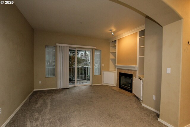 unfurnished living room featuring carpet flooring, a tiled fireplace, and built in features