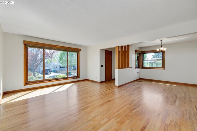 4133 SE Henderson St, Portland, OR 97202 - unfurnished living room featuring baseboards, light wood-style flooring, and a chandelier