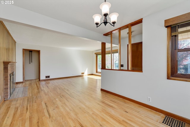 4133 SE Henderson St, Portland, OR 97202 - unfurnished living room with an inviting chandelier, visible vents, a fireplace, baseboards, and light wood-style floors