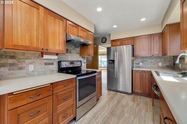 4133 SE Henderson St, Portland, OR 97202 - kitchen featuring decorative backsplash, appliances with stainless steel finishes, brown cabinets, a sink, and under cabinet range hood