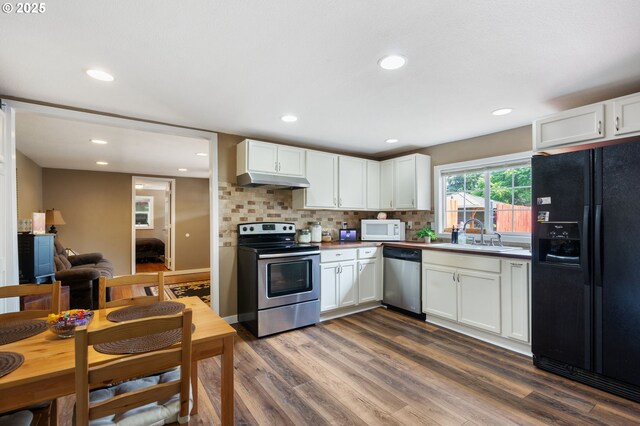 9819 SE Knight St, Portland, OR 97266 - kitchen featuring stainless steel appliances, under cabinet range hood, dark wood-style floors, white cabinetry, and recessed lighting