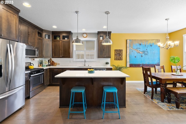 14665 Catalpa Way, Oregon City, OR 97045 - kitchen with appliances with stainless steel finishes, a sink, dark brown cabinetry, a chandelier, and light countertops
