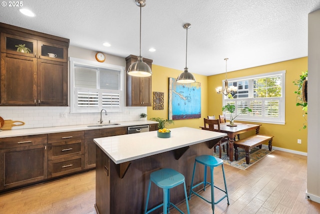 14665 Catalpa Way, Oregon City, OR 97045 - kitchen with a sink, light wood-style floors, a kitchen breakfast bar, light countertops, and a textured ceiling