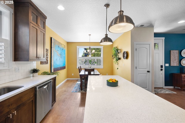 14665 Catalpa Way, Oregon City, OR 97045 - kitchen with stainless steel dishwasher, light wood-type flooring, light countertops, baseboards, and hanging light fixtures