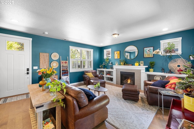 14665 Catalpa Way, Oregon City, OR 97045 - living area with wood finished floors, a glass covered fireplace, a textured ceiling, and recessed lighting
